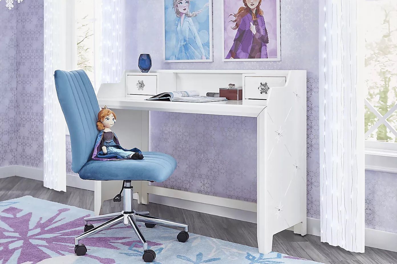 A white desk with drawers, a blue chair, and a Frozen-themed rug.
