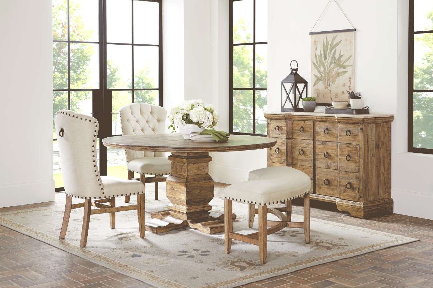 Dining room set with a round wooden table, chairs, and a rug.

