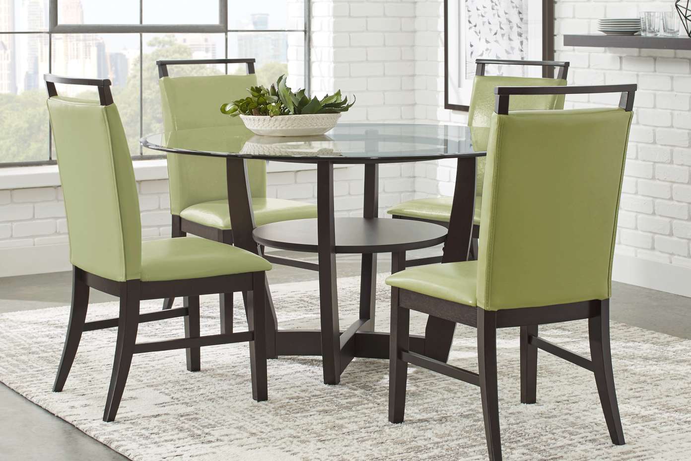 A round dining table with four green chairs.
