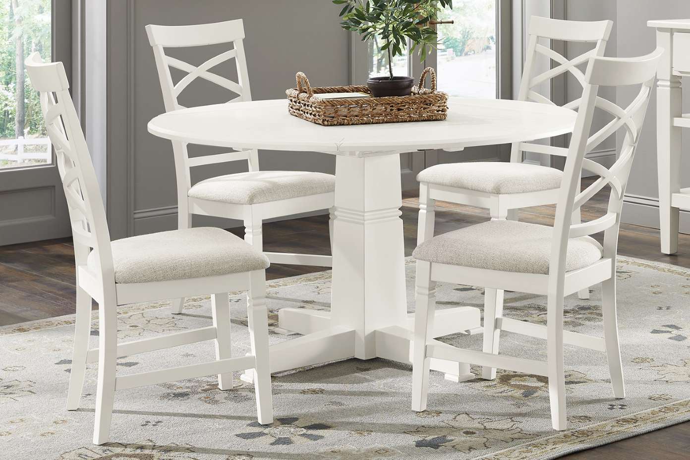 White round dining table with four matching chairs on a patterned rug.