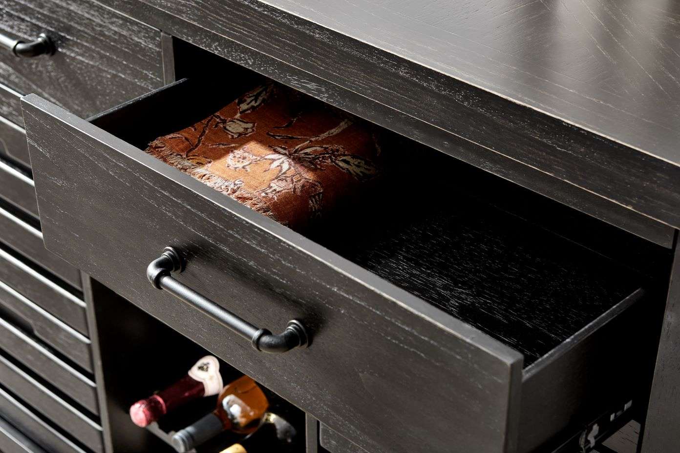 Black wooden cabinet with an open drawer containing a patterned cloth.