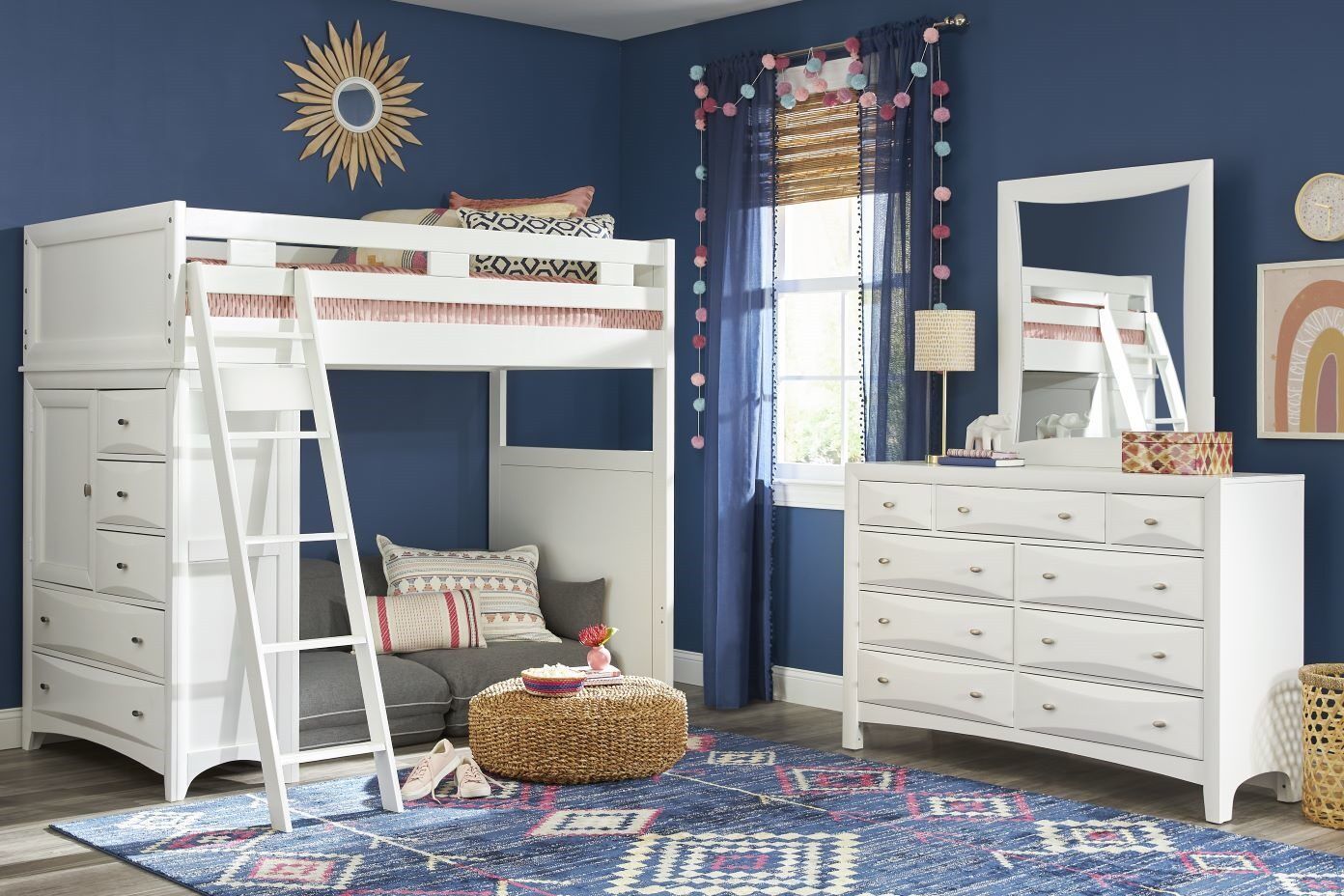 White loft bed with a built-in dresser and a small sofa underneath. A white dresser and a rug are also in the room.
