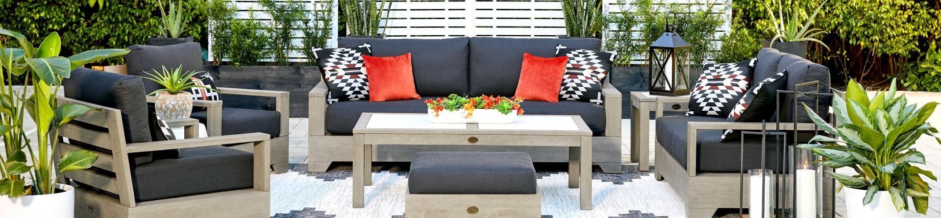 Outdoor furniture set with gray cushions, orange pillows, and a white coffee table.