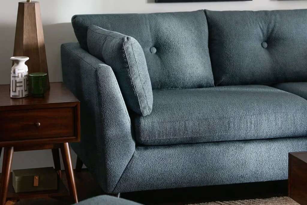 Blue fabric sofa with a side table and lamp.
