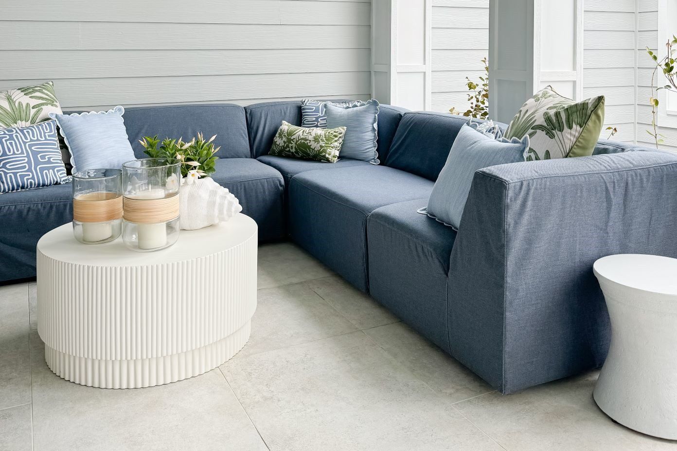 Blue sectional sofa with decorative pillows and a white coffee table.

