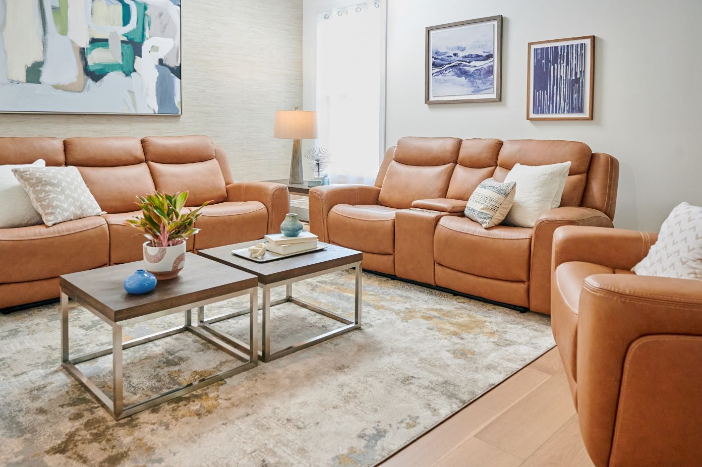 Living room with brown leather furniture, coffee tables, and abstract art.
