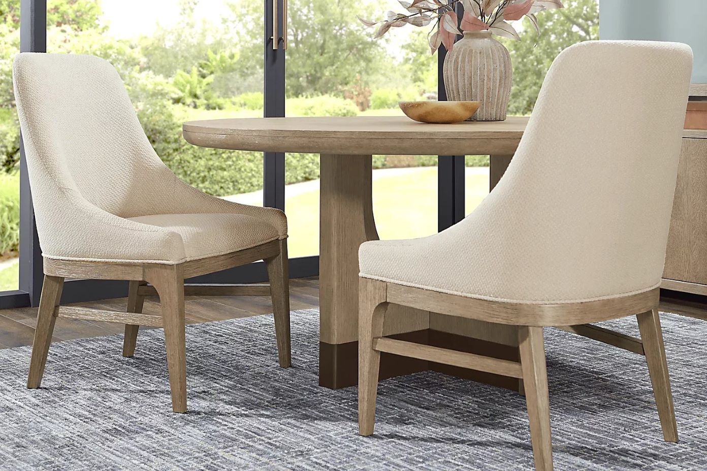 Two upholstered dining chairs with a wooden table.
