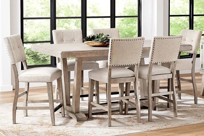 A dining table with six upholstered bar stools.
