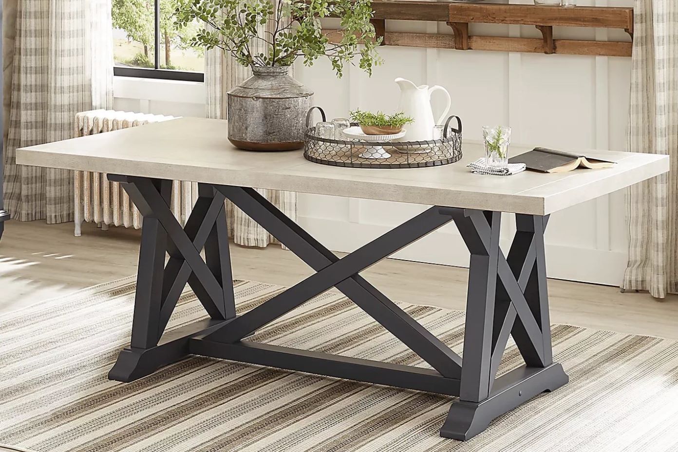 Dining table with a light-colored top and dark gray crisscross legs.
