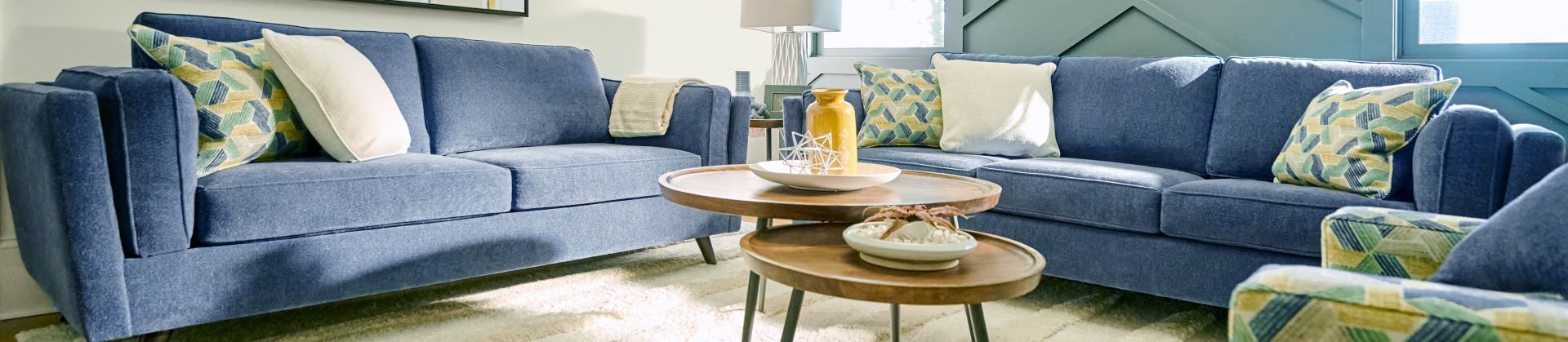 Blue sofas with patterned pillows and wooden coffee tables.
