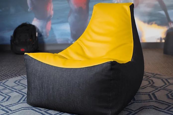 A beanbag chair with a yellow top and black sides.
