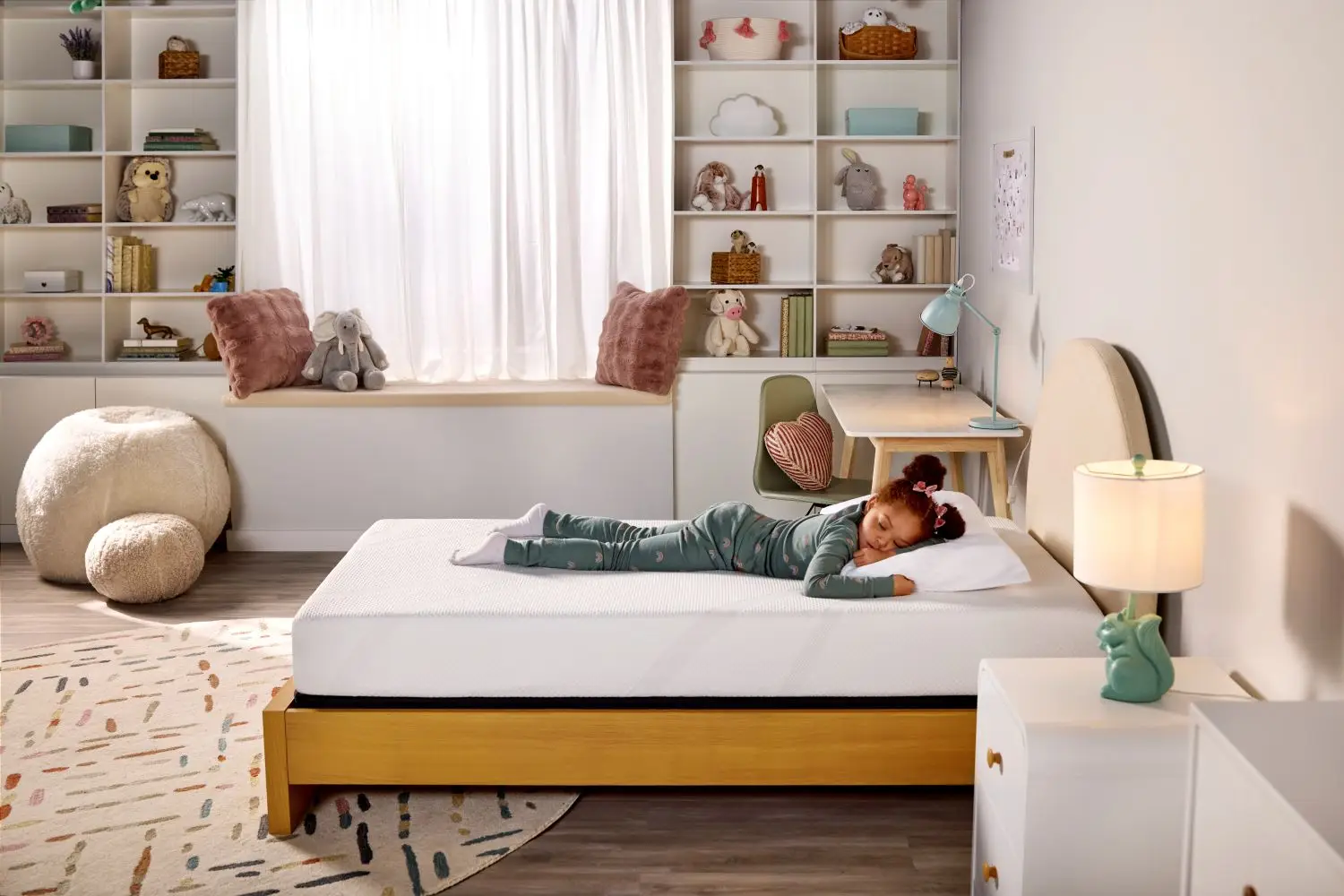 A young girl sleeping on a white memory foam mattress on a wooden bed frame in a cozy, decorated child's bedroom.