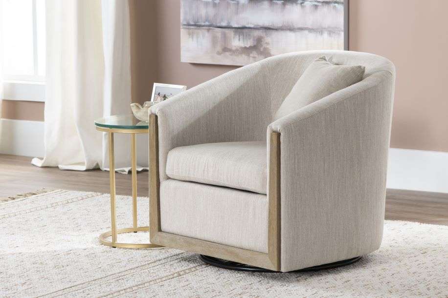 A beige swivel armchair with wooden accents, a side table, and a rug.
