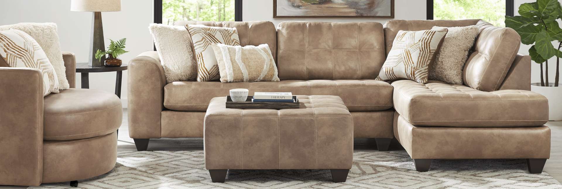 Tan sectional sofa with matching ottoman and accent pillows.
