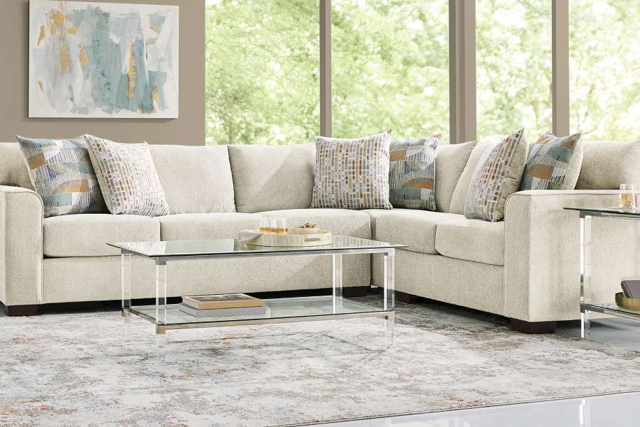 Beige sectional sofa with patterned throw pillows and a glass coffee table.