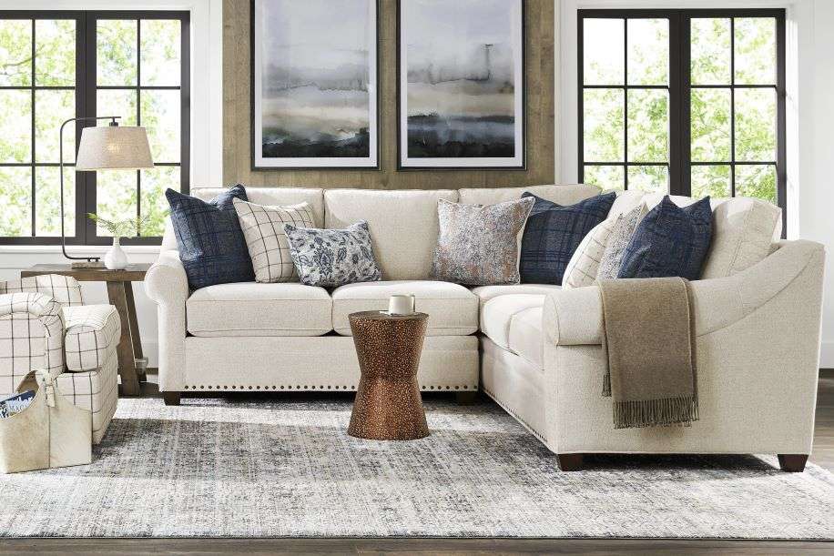 Cream-colored sectional sofa with blue pillows, a patterned rug, and a side table.