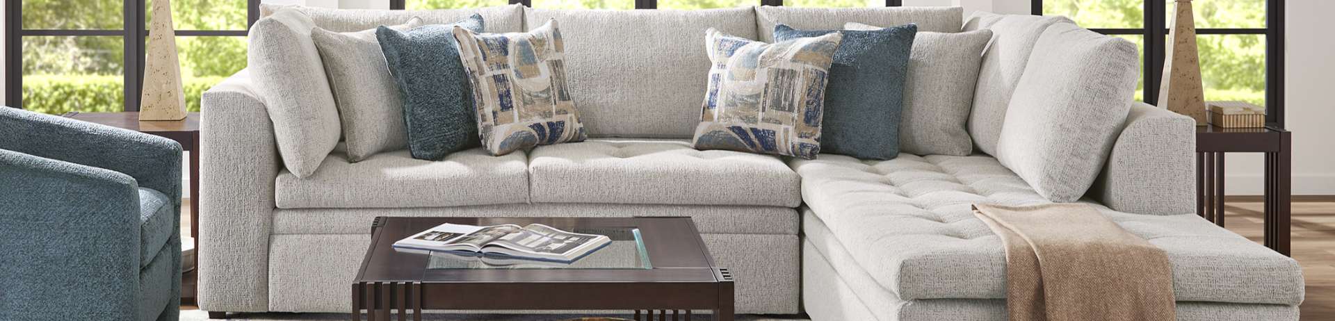 Light gray sectional sofa with patterned pillows and a coffee table.
