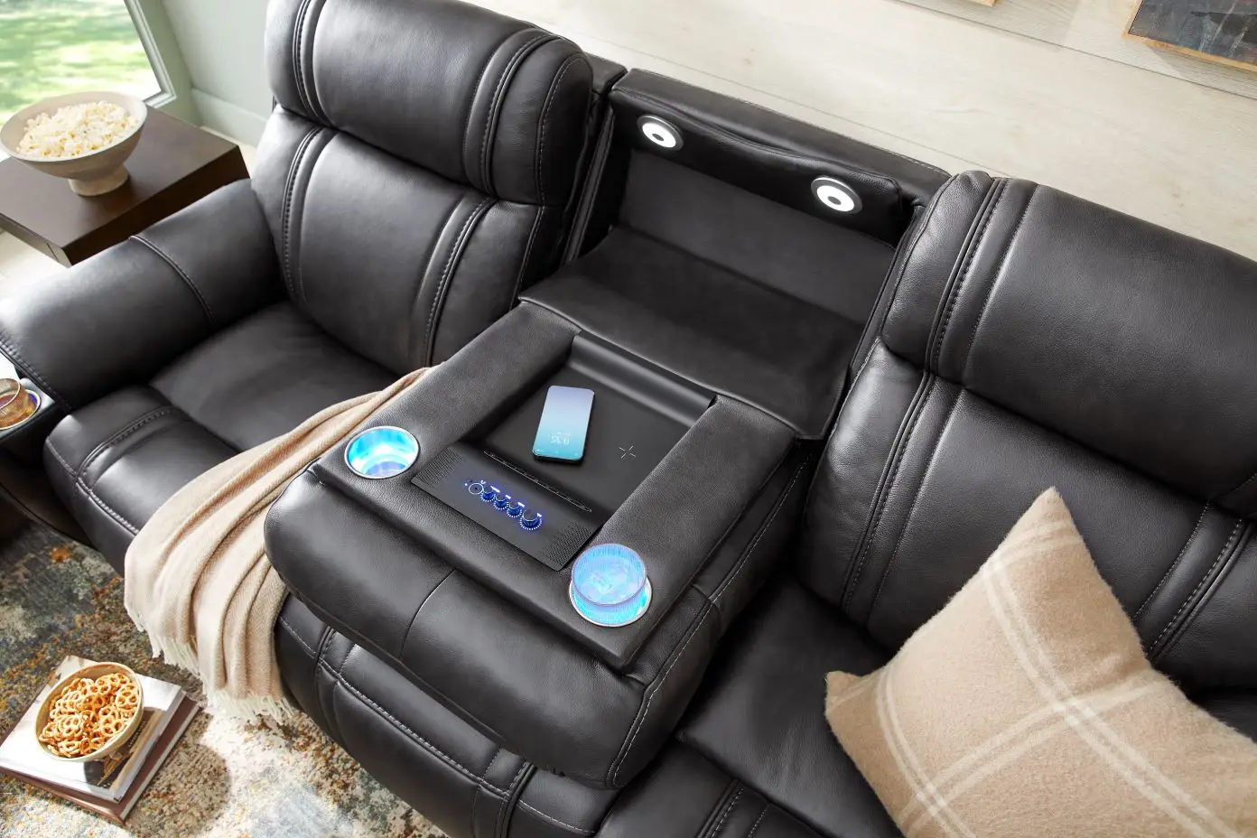 Black leather sectional sofa with built-in features, including cup holders, lights, and a charging station.
