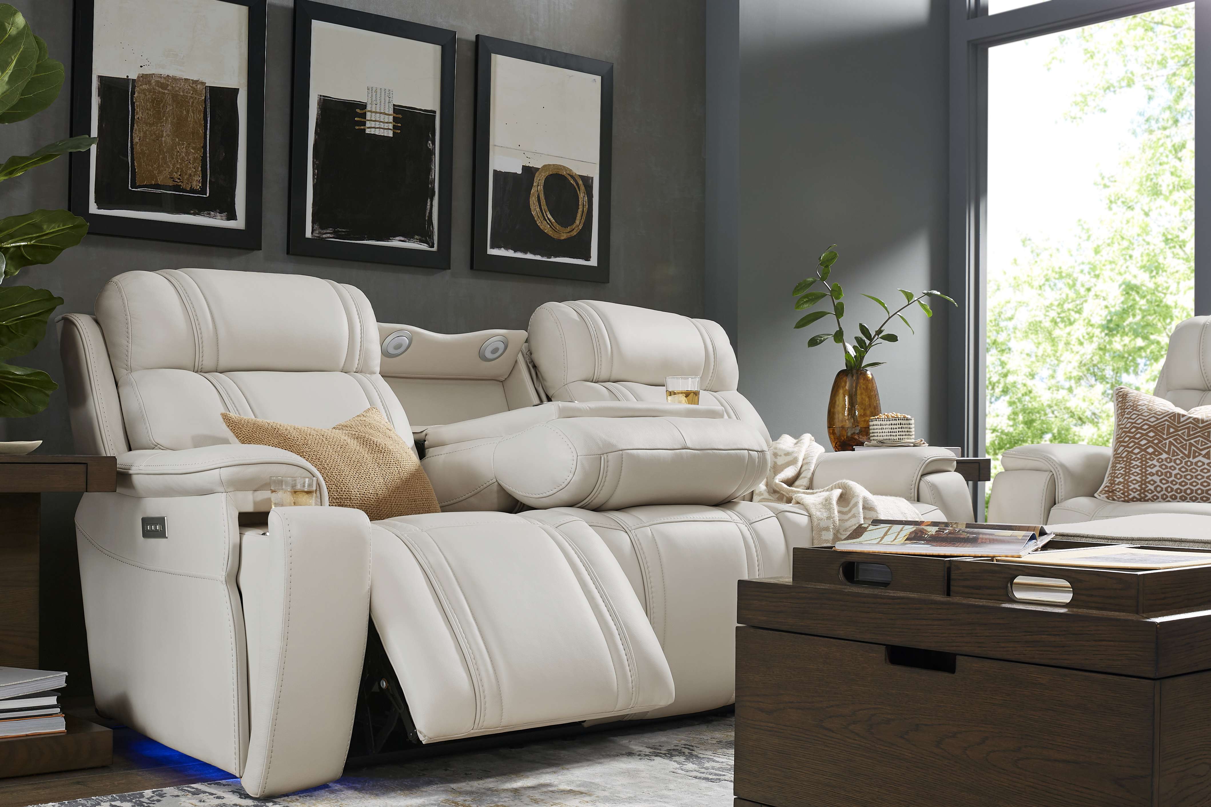 Cream-colored leather reclining sofa with built-in cup holders and side tables.
