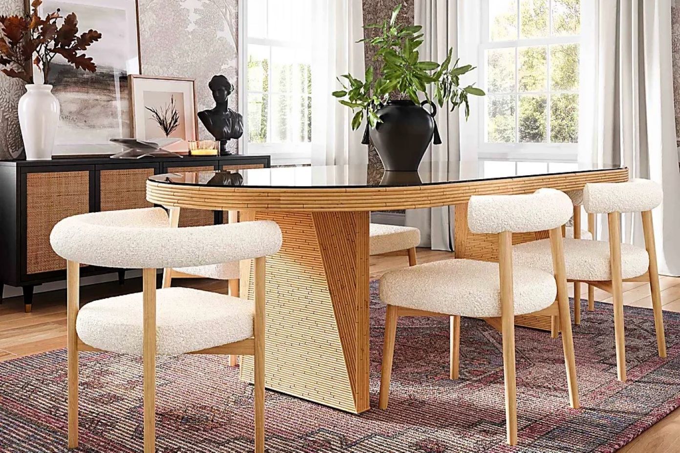 Dining room with a glass-topped oval table, bouclé chairs, and a black sideboard.
