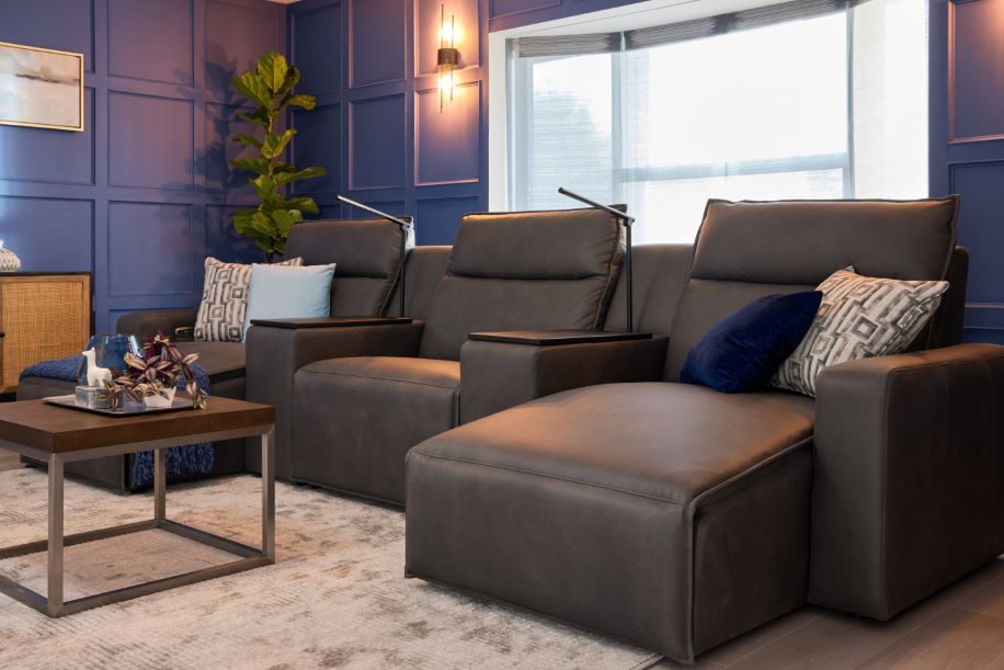 A dark gray leather sectional sofa with a chaise lounge, pillows, and a coffee table.
