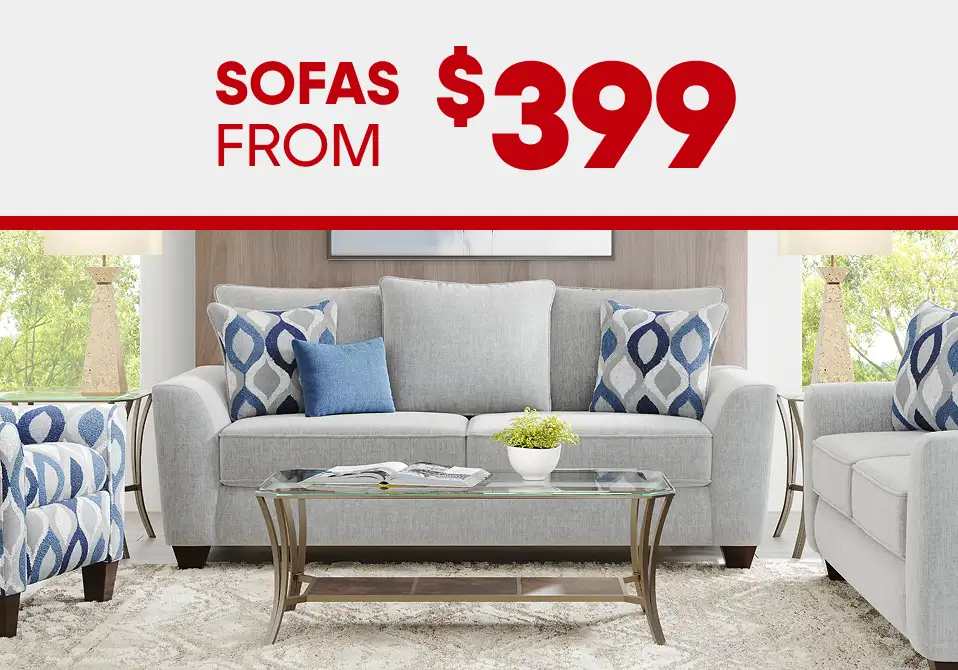 SOFAS FROM $399. A light gray sofa with patterned pillows, a glass coffee table, and a patterned rug.
