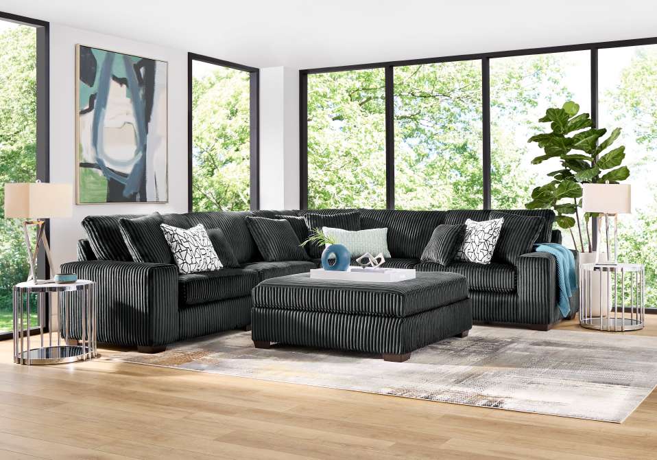 A sectional sofa with an ottoman in a living room with large windows.