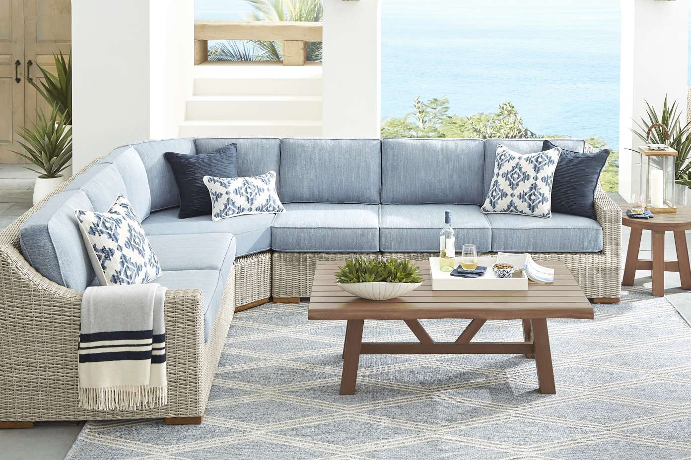 Outdoor sectional sofa with blue cushions and patterned pillows.
