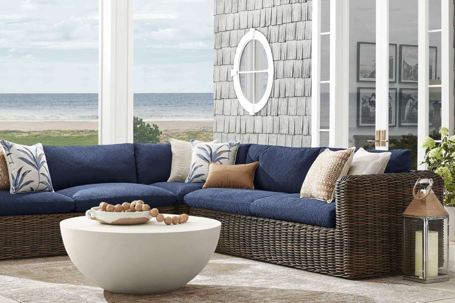 Blue sectional sofa with decorative pillows, a white coffee table, and a lantern.
