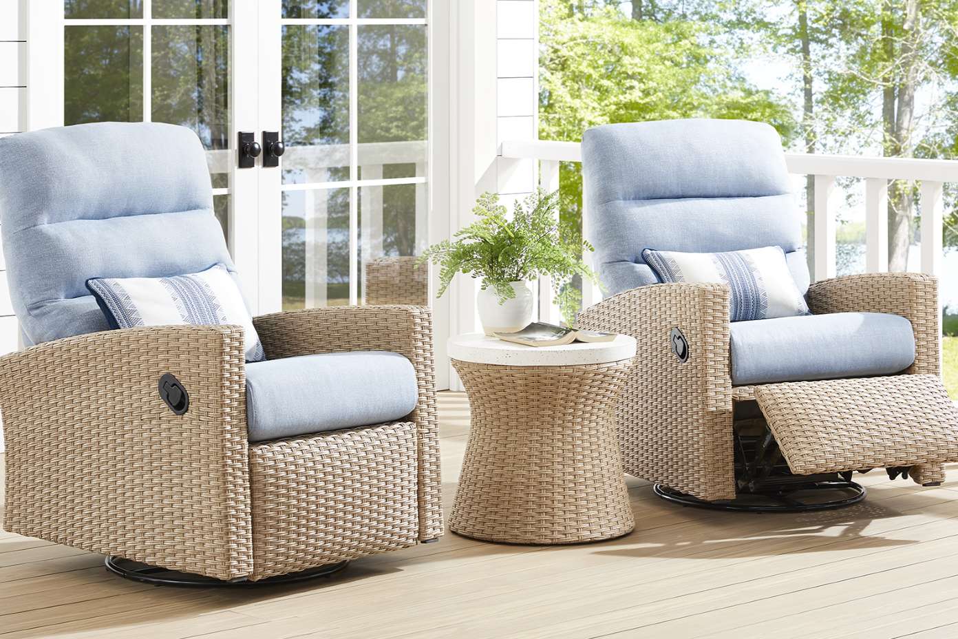 Two wicker outdoor recliner chairs with blue cushions and a small side table.
