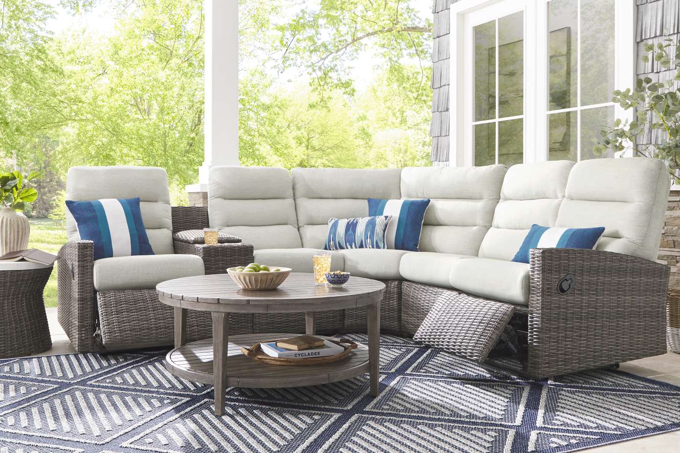 Outdoor sectional sofa with blue and white pillows on a patterned rug.
