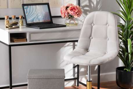 A modern desk with a laptop, chair, and decorative items.
