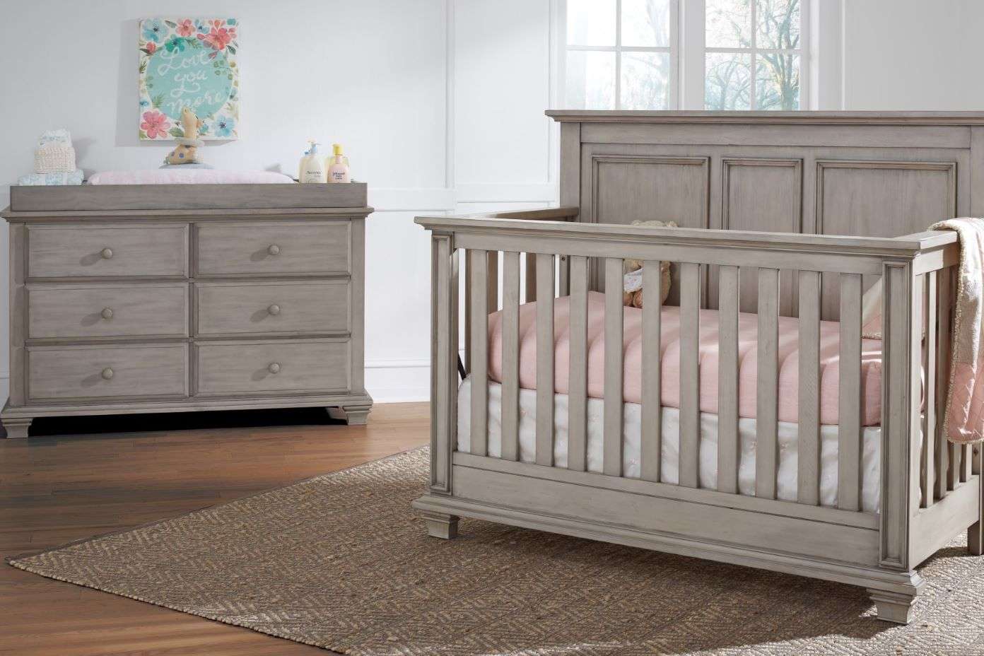 A baby crib and dresser set in a nursery.
