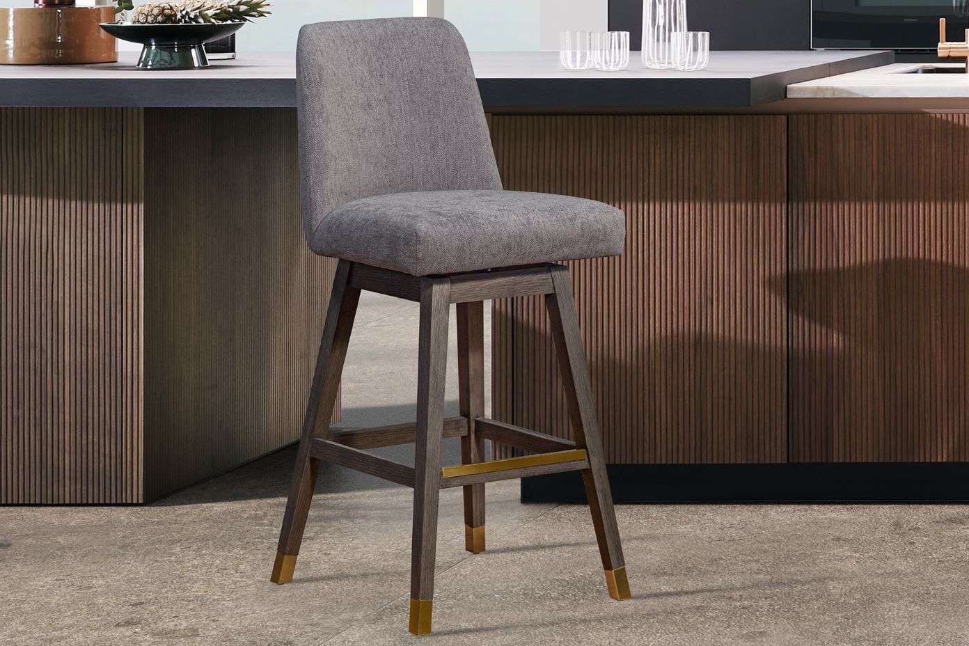Gray upholstered bar stool with wooden frame and brass accents.
