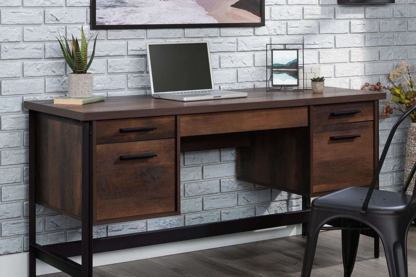 Wooden desk with drawers, a laptop, and a black chair.