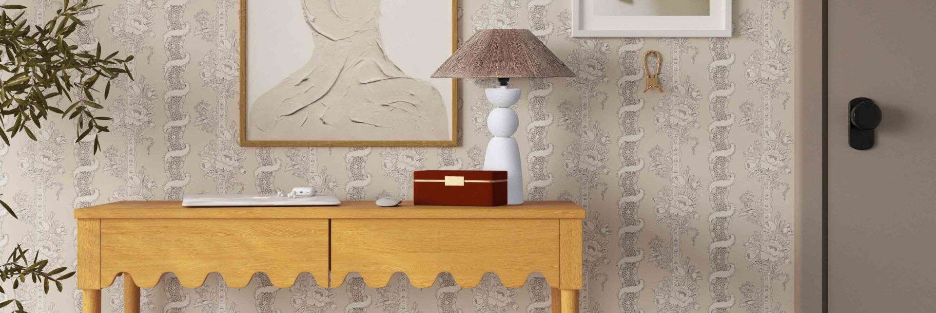 A wooden console table with a lamp, artwork, and a red box.