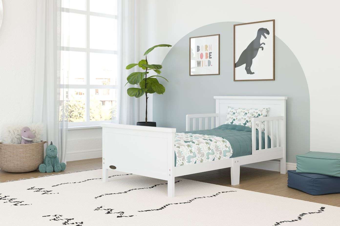 White toddler bed in a child's room with dinosaur-themed decor.