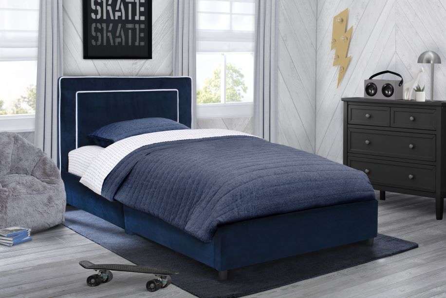 A navy blue bed with a skateboard in a bedroom.