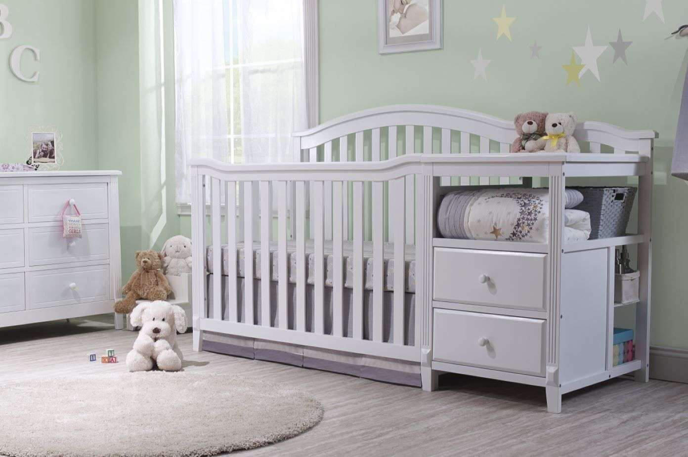 White crib with changing table, drawers, and shelves in a nursery.