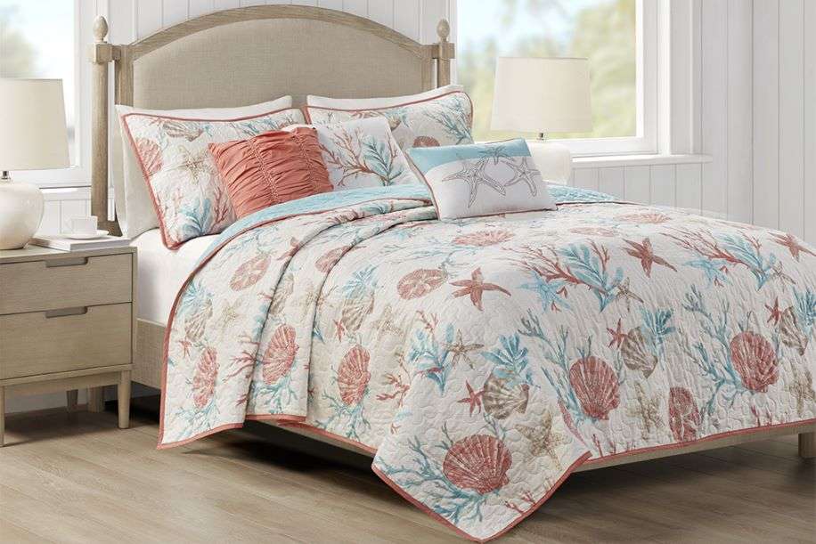Bed with a seashell-patterned quilt and pillows.
