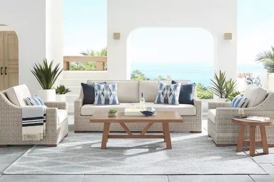 Cozy screened-in porch with wicker furniture, blue accents, and a fall foliage view