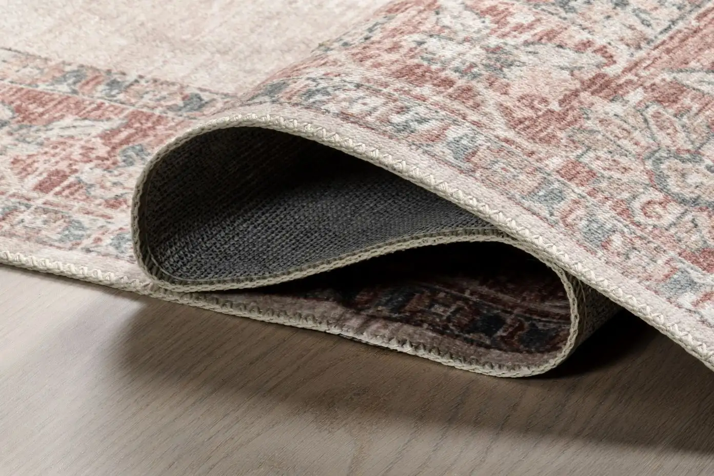A rolled-up rug with a patterned design in shades of red, gray, and beige.
