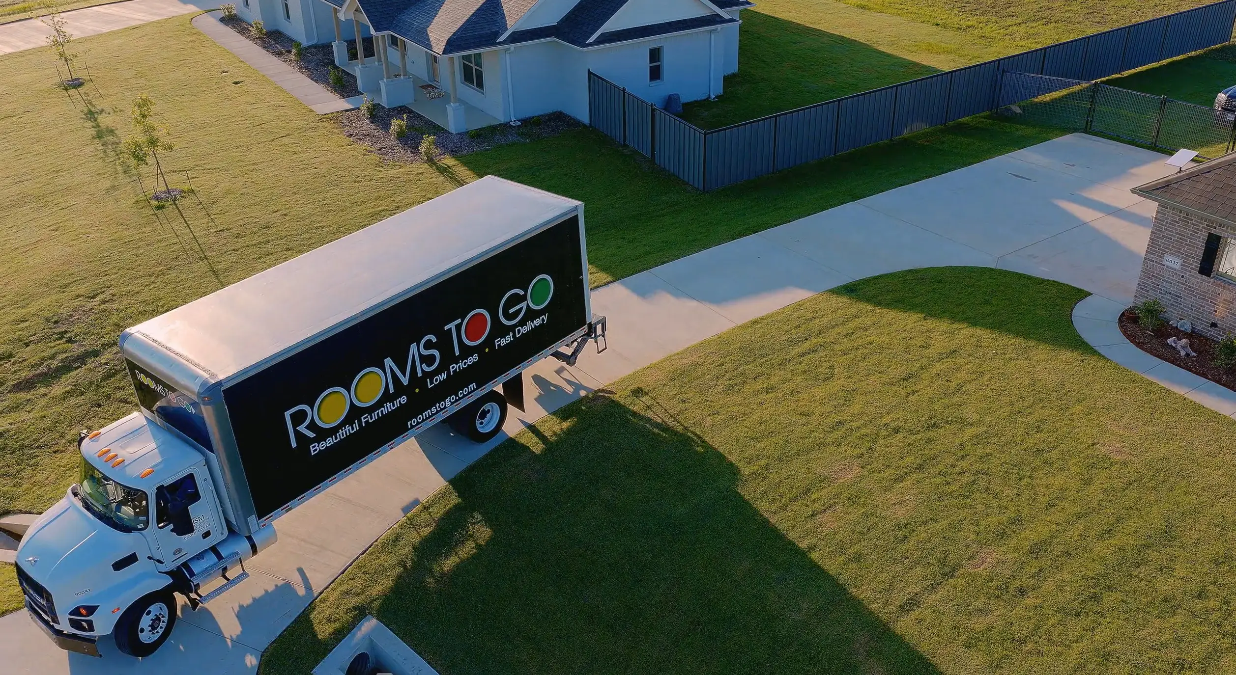 Rooms To Go delivery truck parked in a residential driveway.