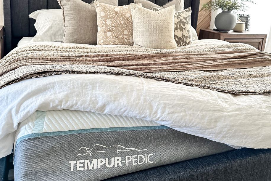 TEMPUR-PEDIC mattress on a bed with pillows and blankets.
