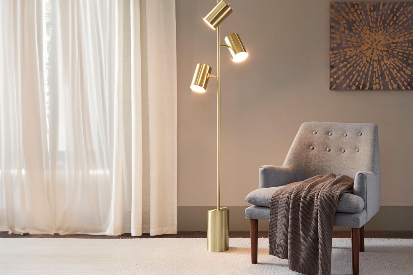 Modern living room with gray armchair, brass floor lamp, and sheer curtains