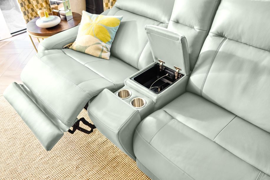 Light gray leather reclining sofa with a center console that has cup holders and a storage compartment.
