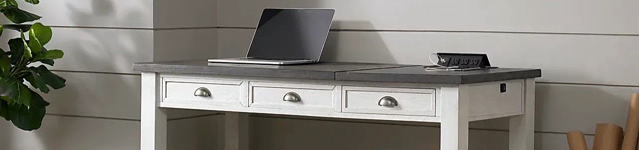 White desk with a gray top, a laptop, and a power strip.
