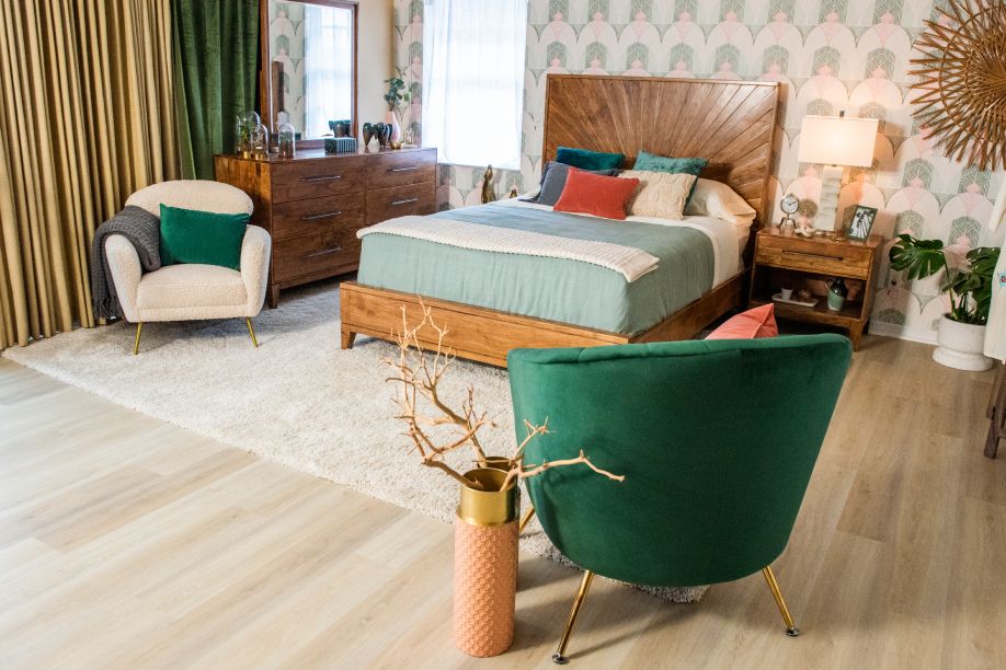 A bedroom with a bed, dresser, and green velvet chair.
