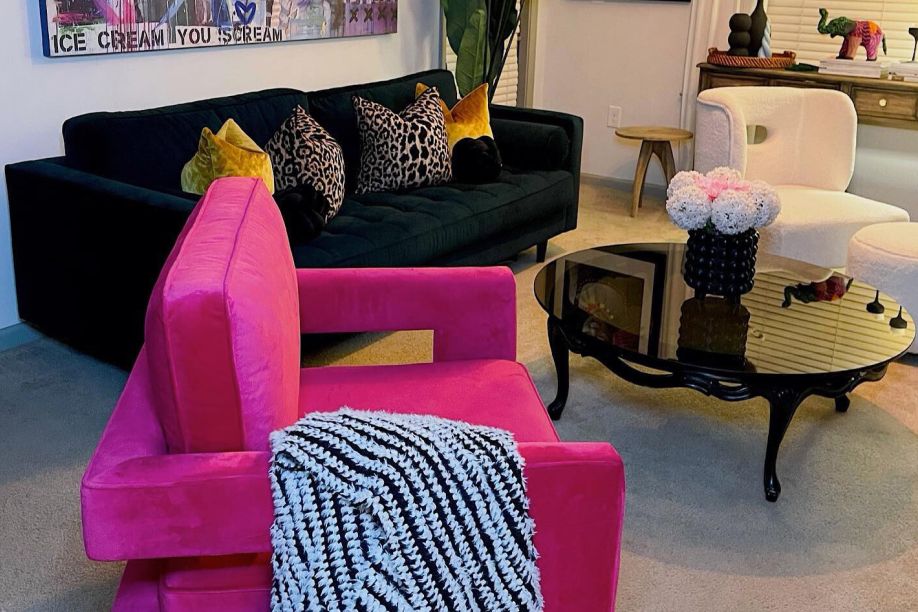 A living room with a pink chair, a dark green sofa, and a black coffee table.
