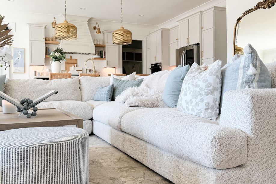 A large, white sectional sofa with decorative pillows in a living room.
